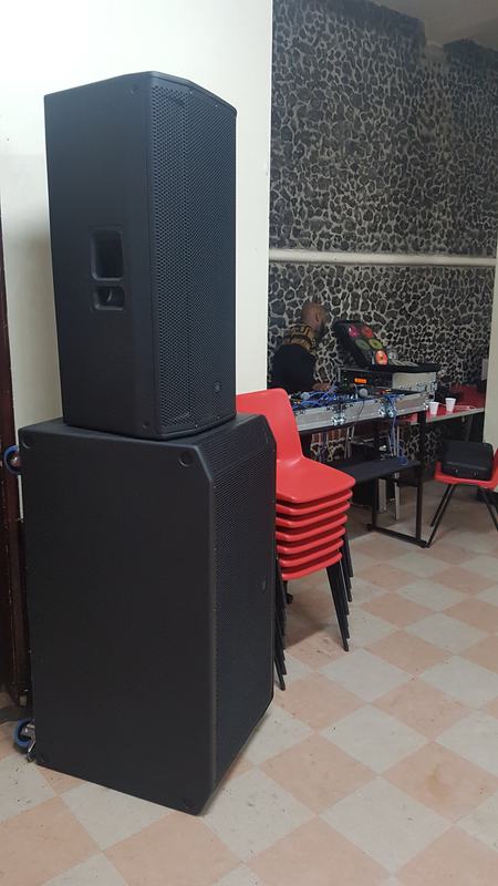 JBL PA stack with DJ setting up in the background