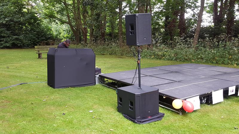 Outdoor garden event with staged PA speakers and DJ booth