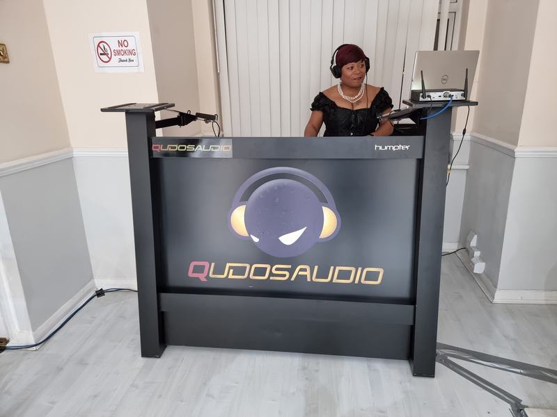 DJ performing behind the branded Qudos Audio DJ booth